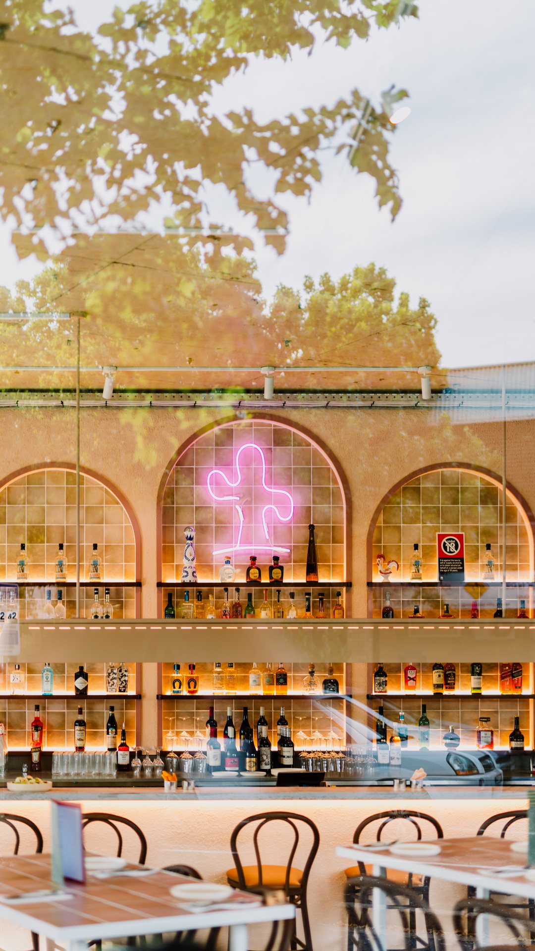 Restaurant interior with arched windows, a neon cactus and a long bar